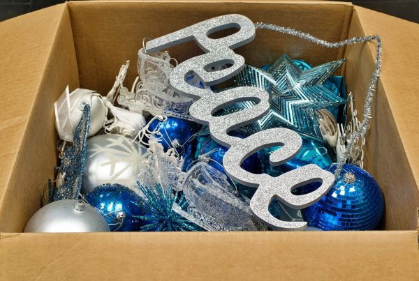 Christmas ornaments and a peace sign decoration in an open cardboard box